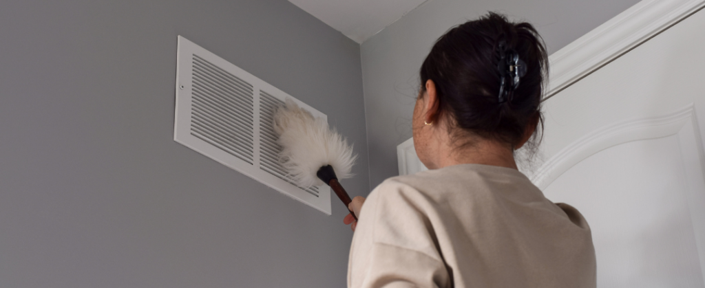 Lady dusting the vents to improve the air quality in the bedroom