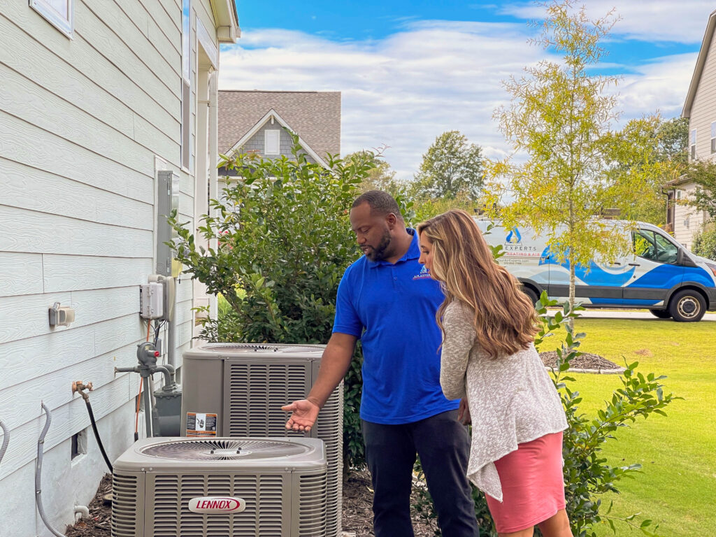 One of our technicians is showing a customer the outside unit of their new HVAC system.