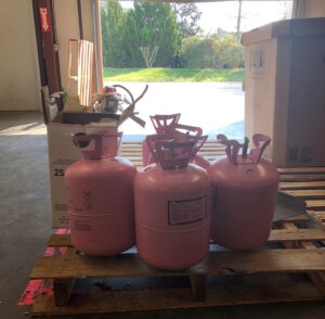 Picture of four pink canisters of R-410A refrigerant. 