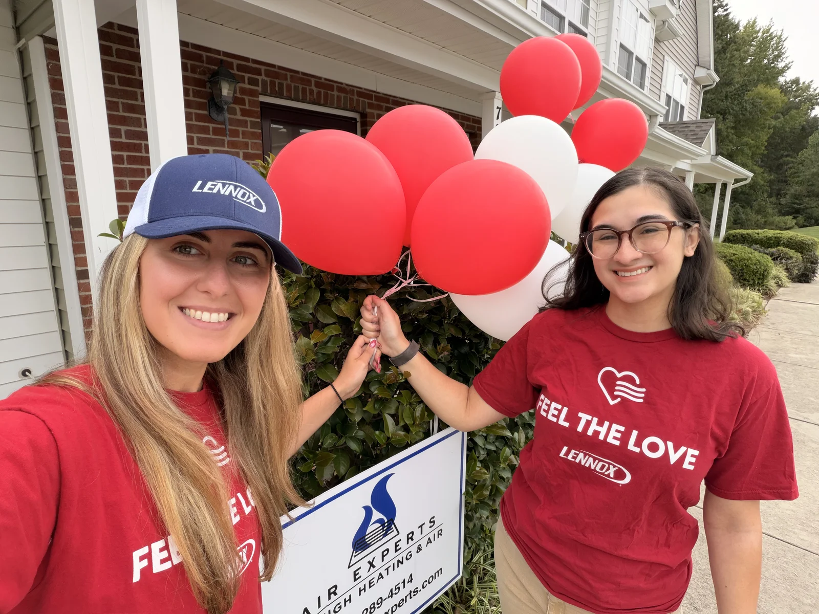 REVIEW: confirm who is pictured before publishing — two people celebrating with Feel the Love balloons and a yard sign