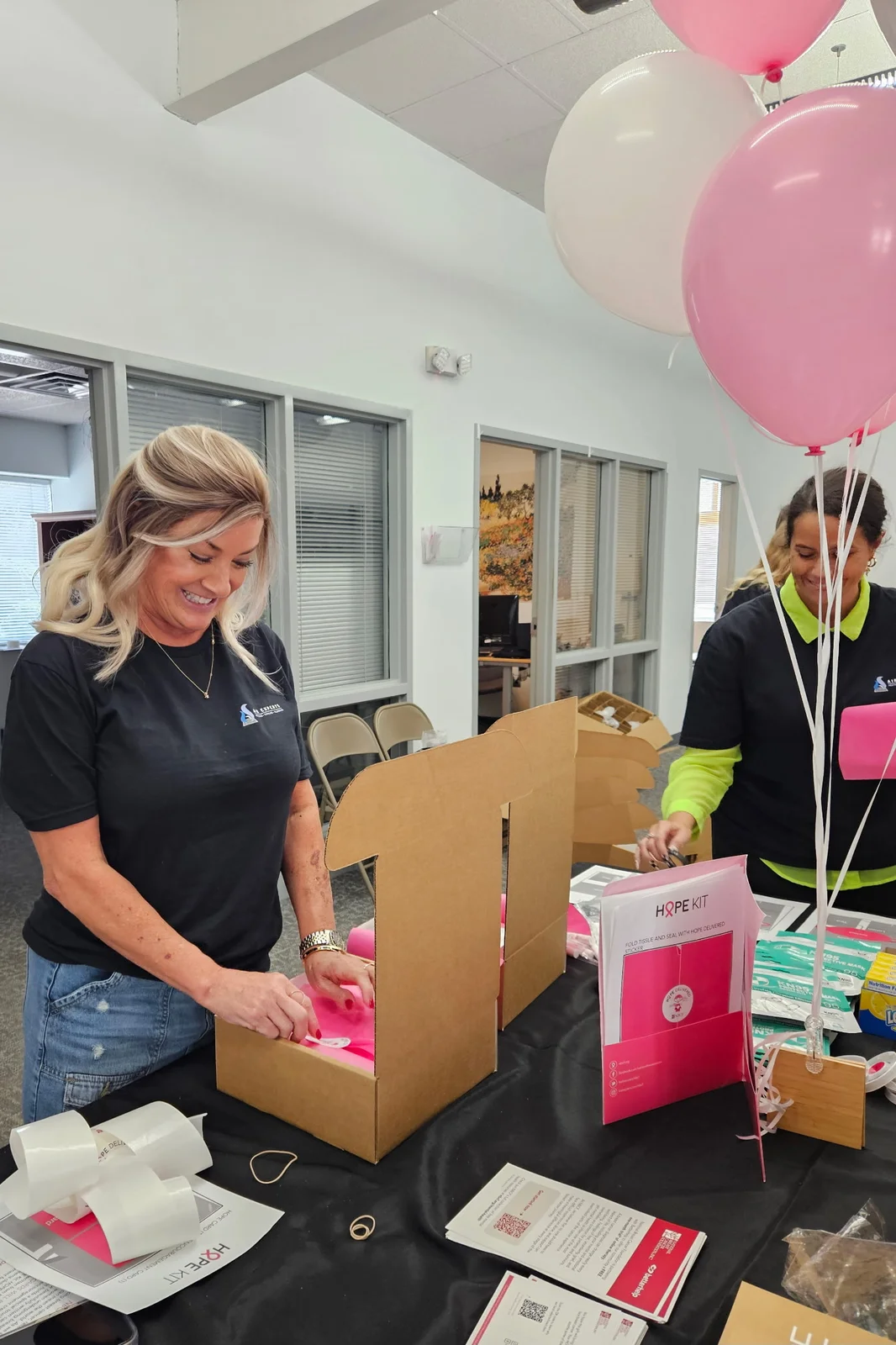 Air Experts employee packing a Hope Kit box beneath pink balloons