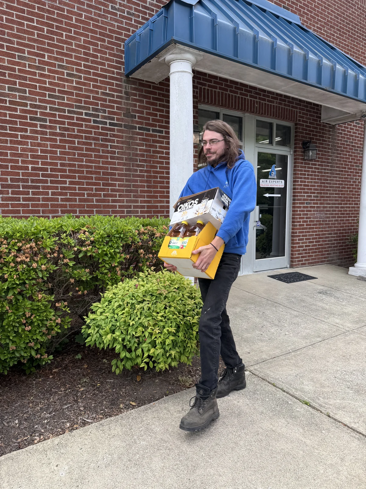 Air Experts employee carrying a box of donated food items