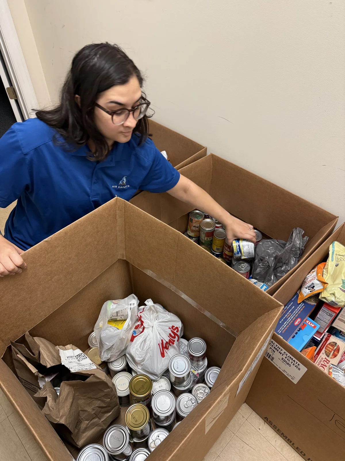 Air Experts employee boxing up donated canned goods and groceries
